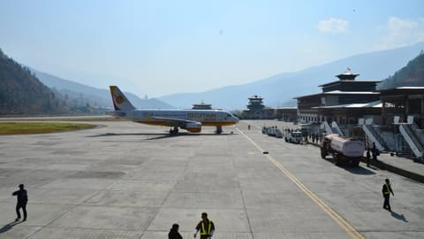 Planes landing on Paro International Airport's stunning runway surrounded by towering mountains.